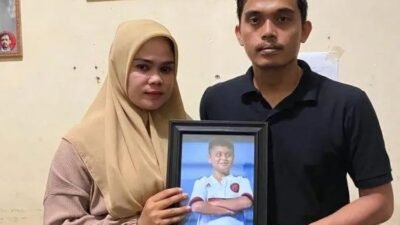 Afrinaldi (36, kanan) dan Anggun (32) berfoto dengan potret Afif Maulana (13), di kantor LBH Padang, Kota Padang, Sumatera Barat.(DOK. LBH PADANG via BBC Indonesia)